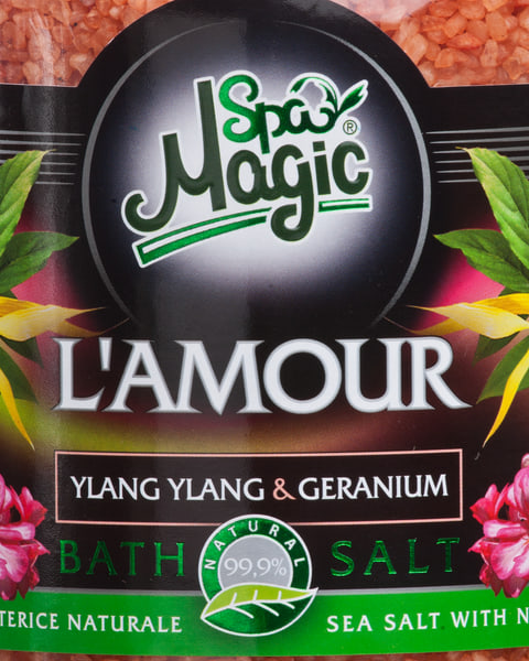 Close-up of the L’Amour label: yellow ylang-ylang flowers and pink geranium either side of the name